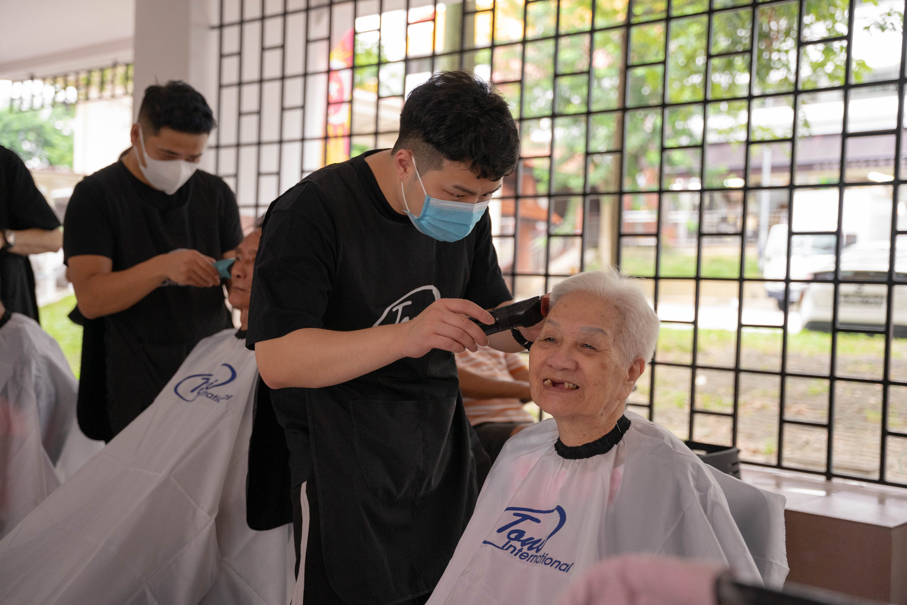 A barber trimming an elderly resident's hair at the Bukit Batok Charity Cut
